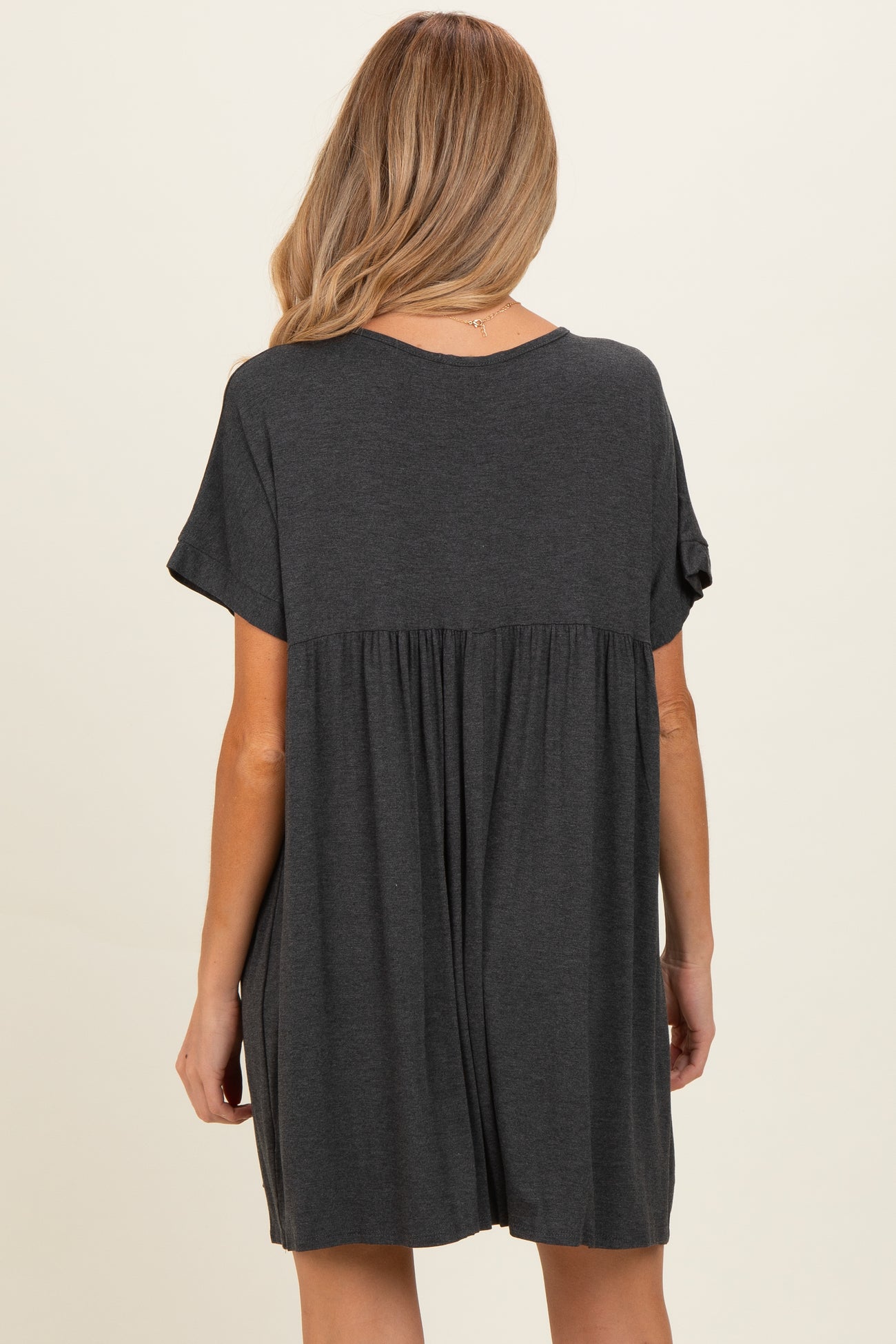 woman wearing a dark gray maternity dress with a flowy back and short sleeves
