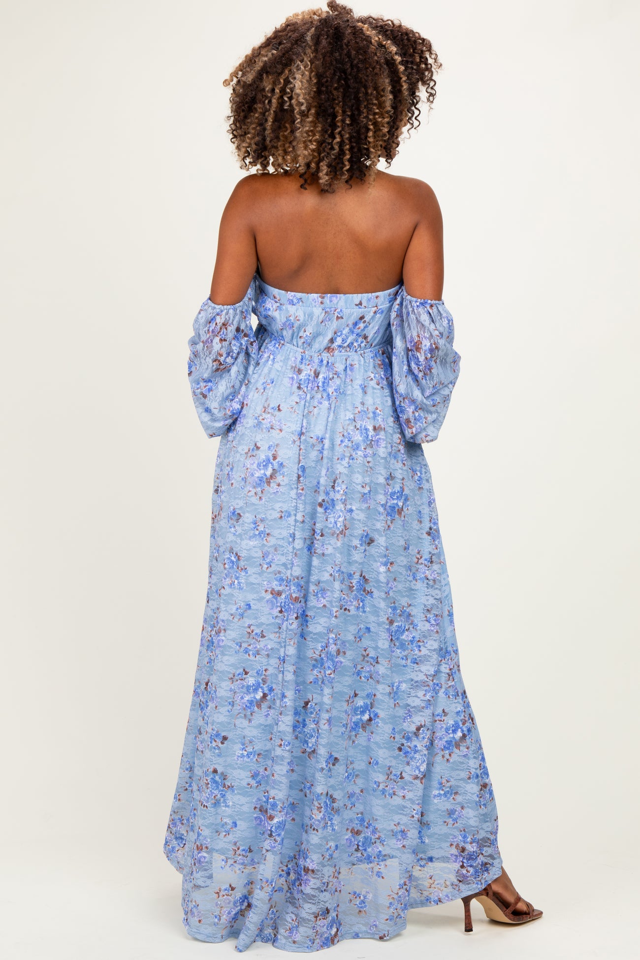 woman wearing a blue floral off-the-shoulder maternity dress with puffed sleeves and a flowing maxi length