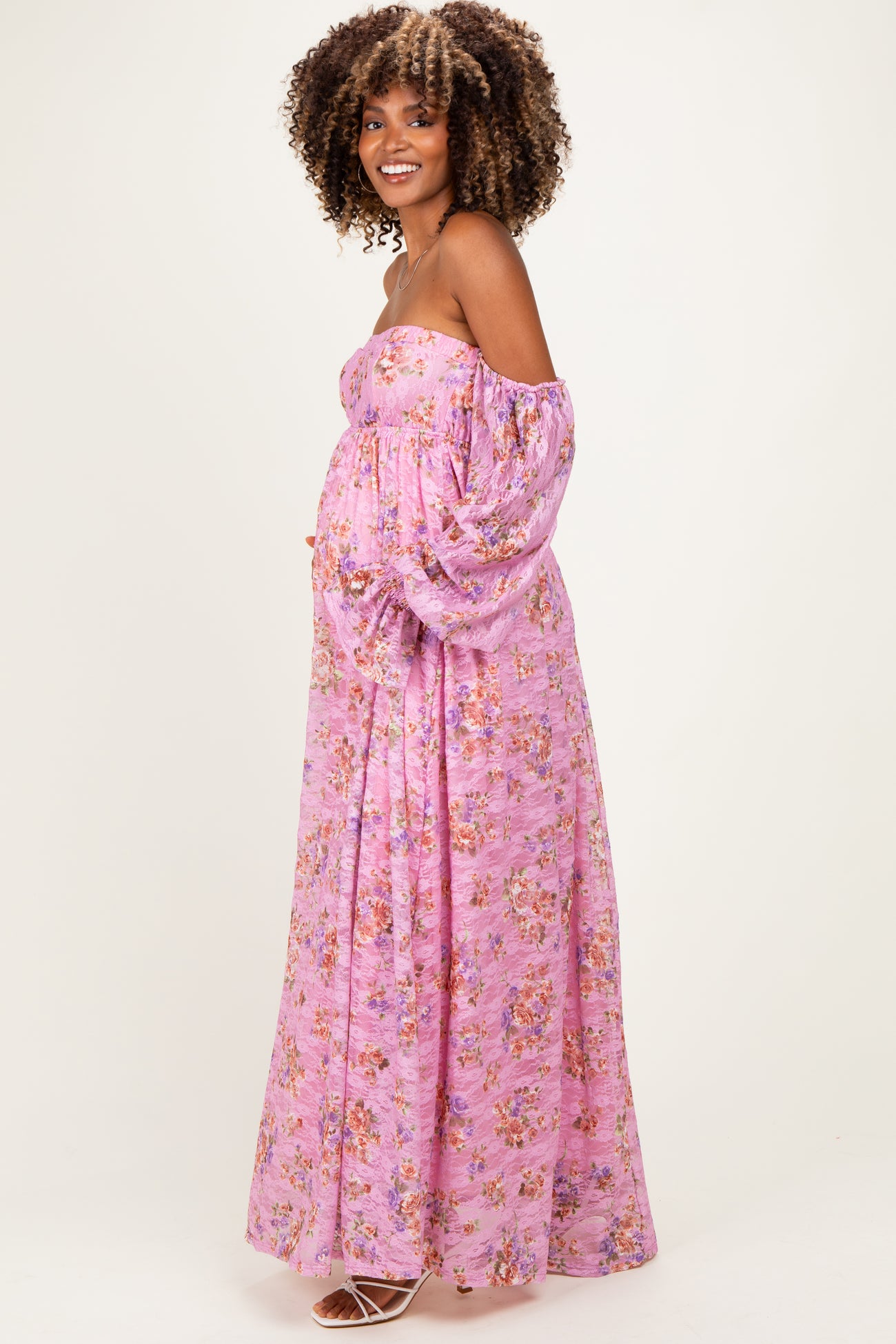 woman wearing a floral off-shoulder pink maternity maxi dress and showing her baby bump