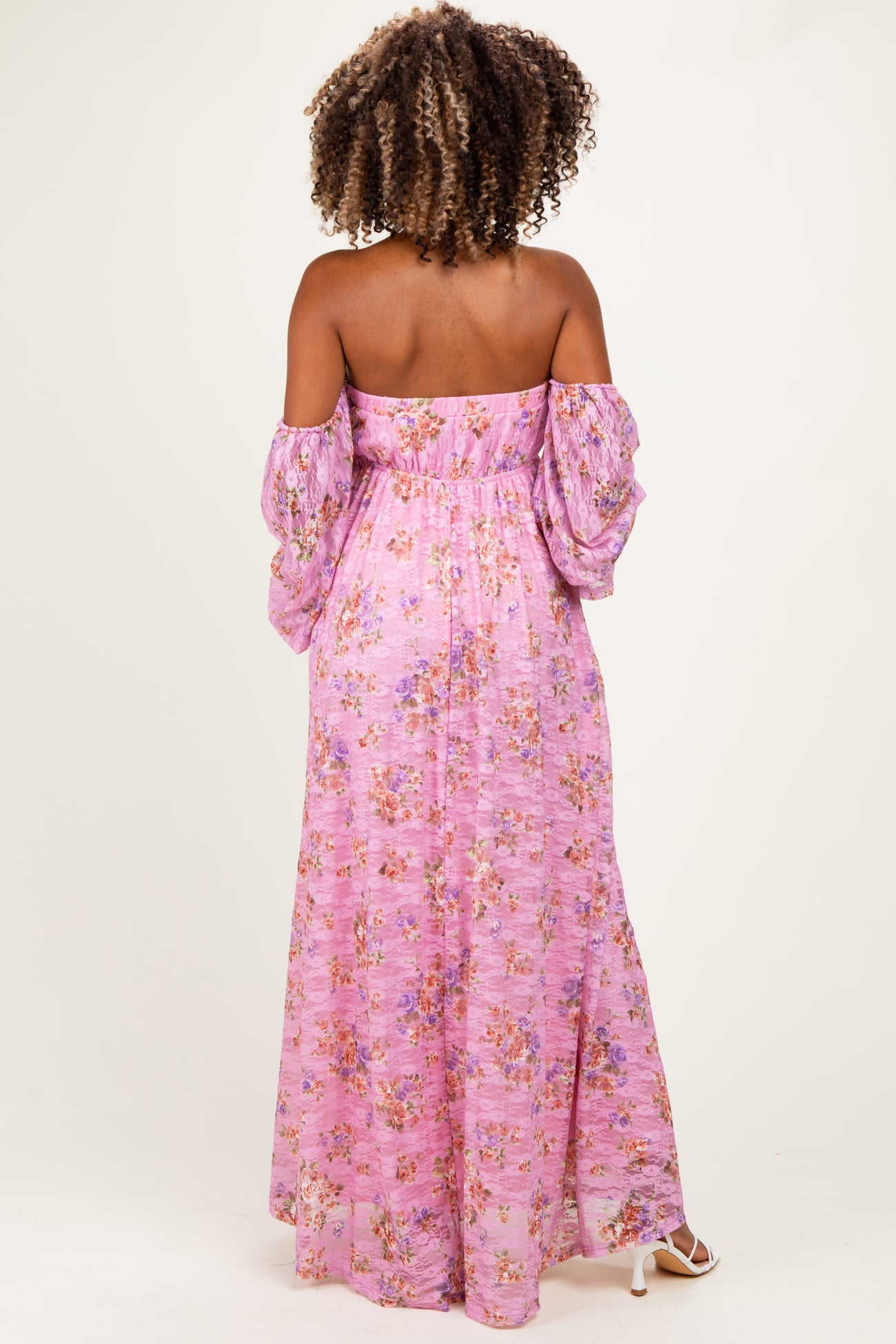 woman wearing a pink floral off-the-shoulder maternity dress with long puffed sleeves and a flowing silhouette