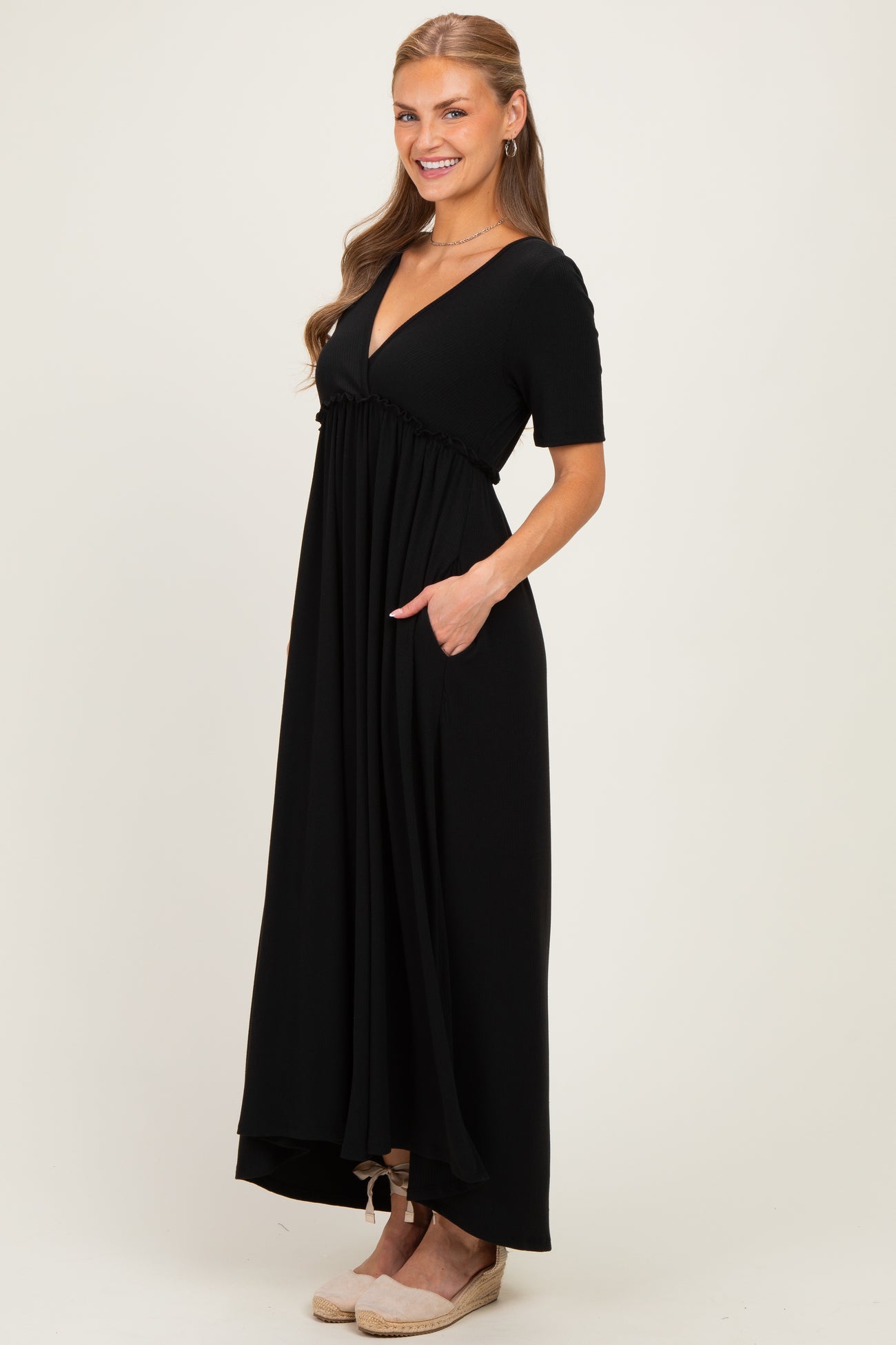 woman wearing a black short sleeve maxi dress with a deep v-neck and pockets, styled with wedge sandals