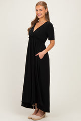 woman wearing a black short sleeve maxi dress with a deep v-neck and pockets, styled with wedge sandals