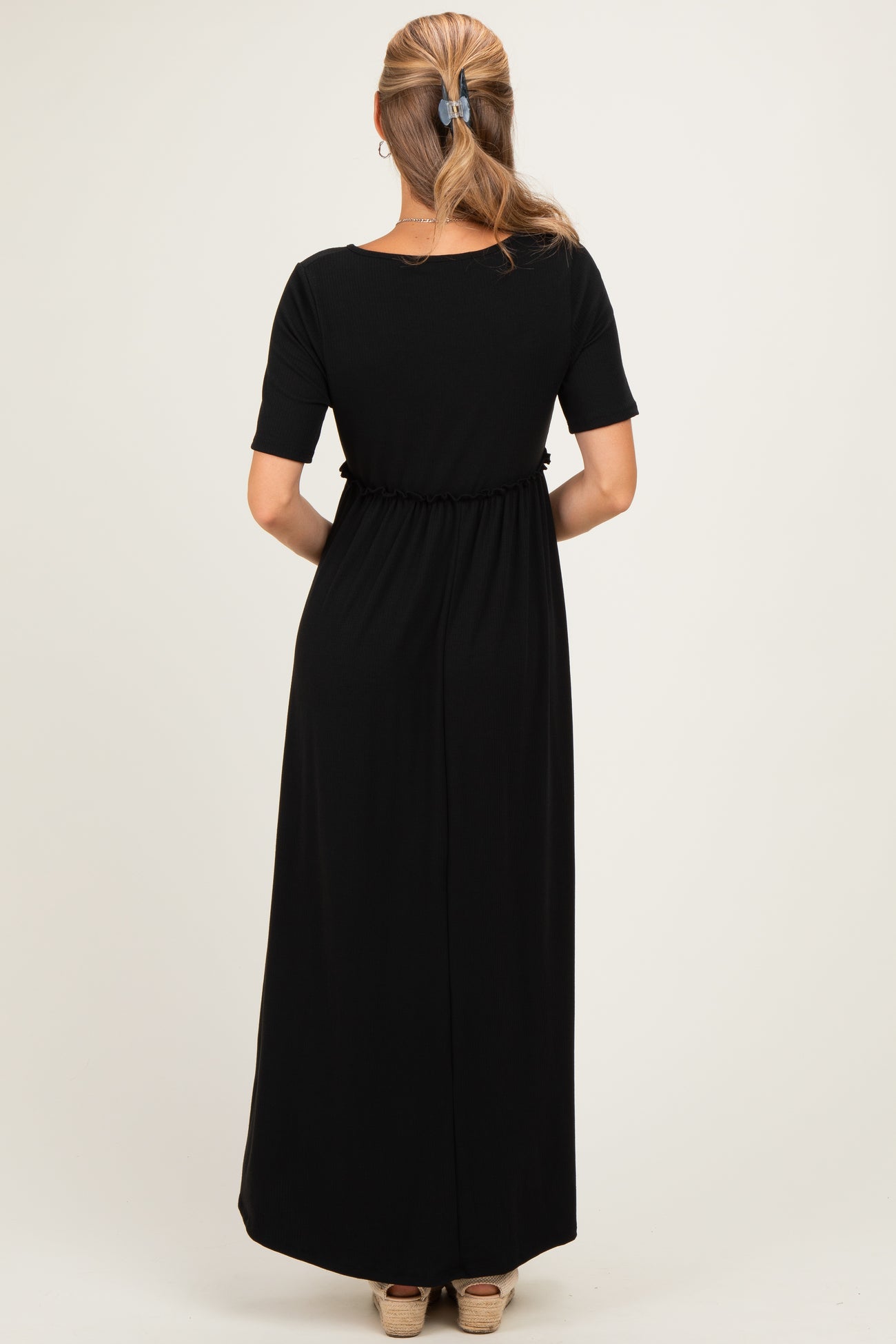 woman wearing a black maxi dress with short sleeves and an elastic waist, seen from the back