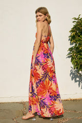 woman wearing a vibrant floral maxi dress with pink, orange, and purple colors, showing a sundress style from the back