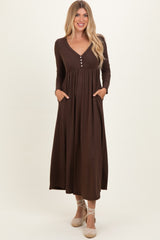 woman wearing a brown long sleeve maxi dress with a v-neck and pockets, styled with buttons down the front