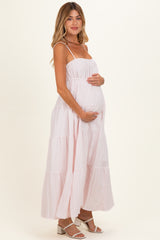 woman wearing a pink and white striped maternity maxi dress and holding her baby bump