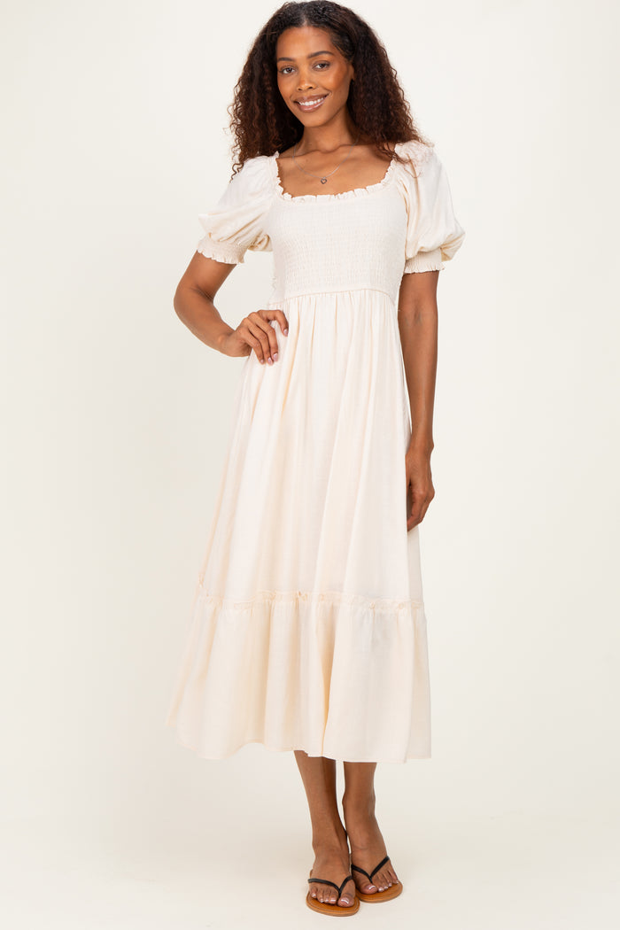 woman wearing a cream puff sleeve maxi dress with a square neckline and smocked bodice