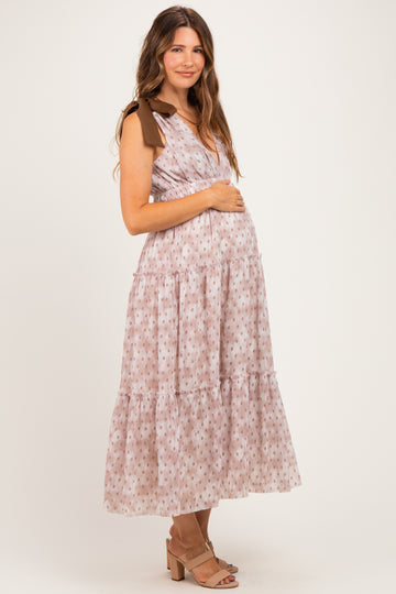 woman wearing a floral print maternity maxi dress with brown tie straps and a visible baby bump