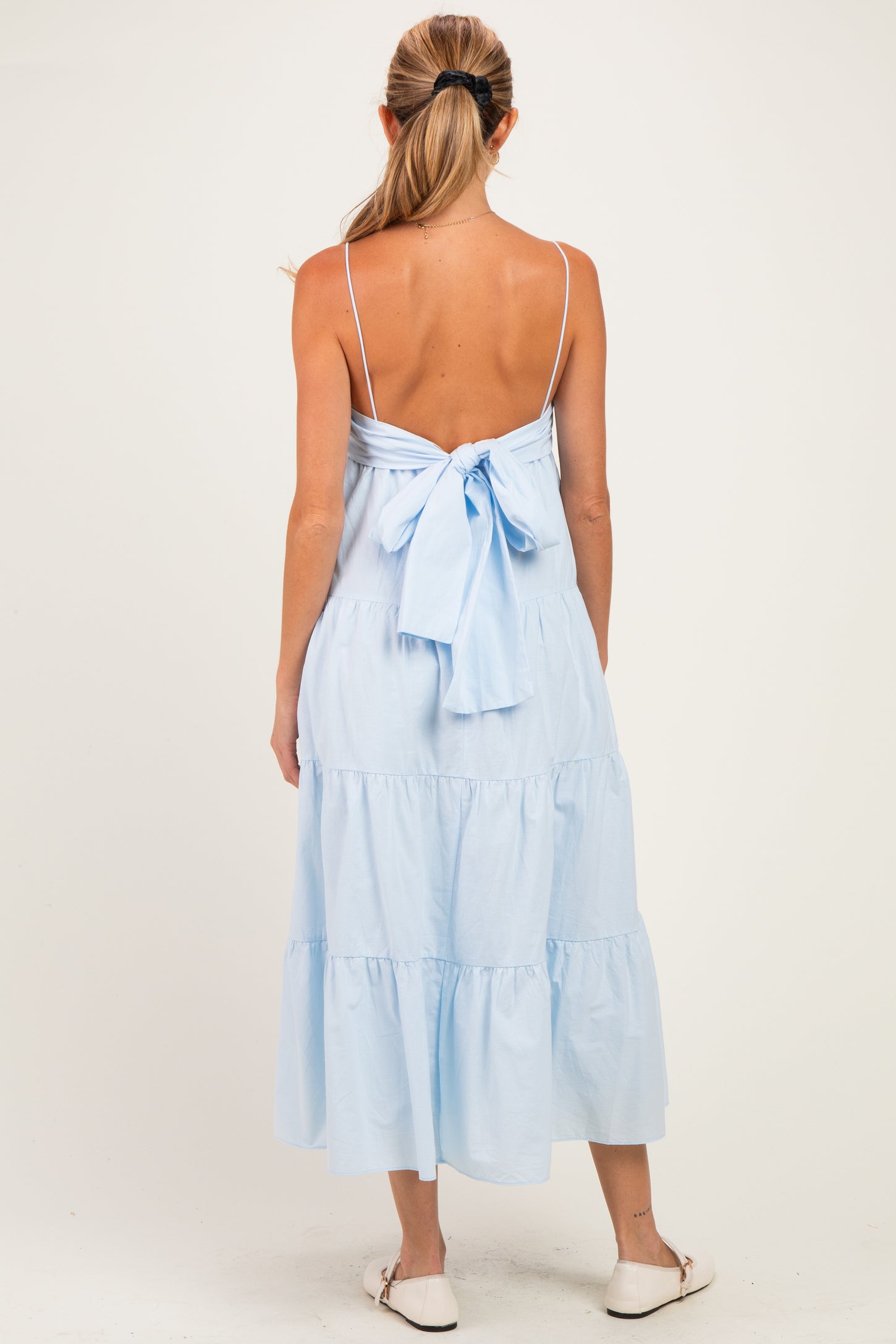 woman wearing a light blue tiered maternity dress with a bow tie detail on the back.