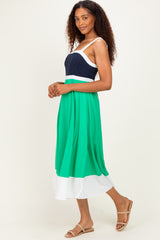woman wearing a color-blocked maxi dress with a navy top, green midsection, and white bottom, styled with tan sandals