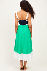 woman wearing a back view of a color-blocked green and navy midi dress with a fitted bodice and flowing skirt