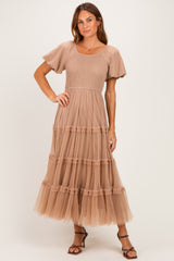 woman wearing a beige puff sleeve maxi dress with a smocked bodice and tiered tulle skirt