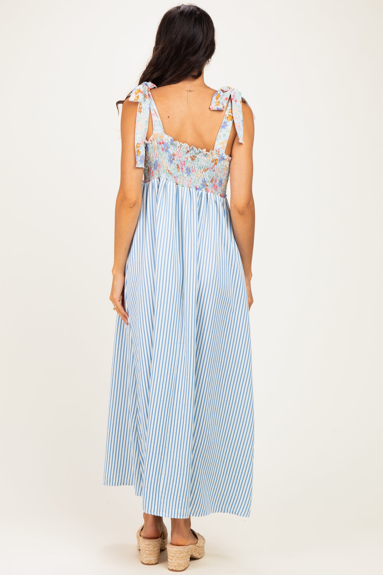 woman wearing a blue and white striped maxi dress with floral smocked bodice and tie straps