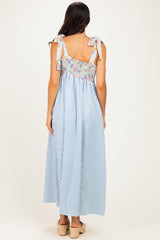 woman wearing a blue and white striped maxi dress with floral smocked bodice and tie straps