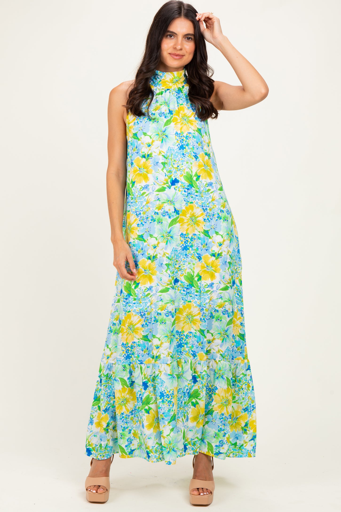 woman wearing a floral halter neck maxi dress in green and yellow hues with a tiered skirt