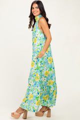 woman wearing a floral maxi dress with a halter neckline and pockets in shades of blue and yellow