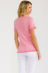 woman wearing a pink short sleeve top with floral pattern and ruffled sleeves, turned slightly away from the camera