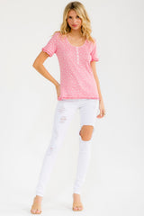 woman wearing a pink short sleeve top with ruffle details and white ripped skinny jeans