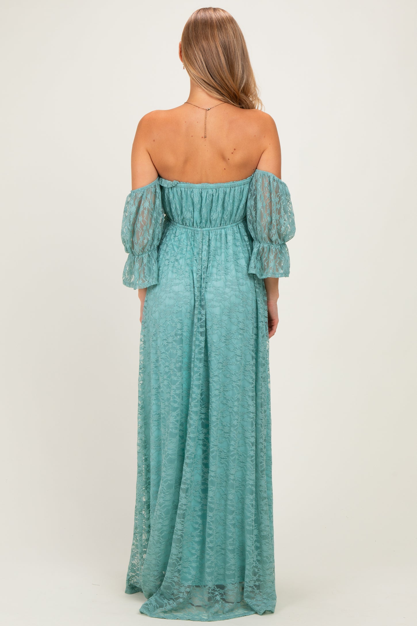woman wearing a teal off-the-shoulder maxi dress with puff sleeves and a gathered waist, seen from the back