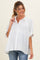 woman wearing a white striped maternity button-up shirt and smiling, with a slightly visible baby bump