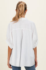 woman wearing a white striped oversized maternity top, viewed from the back, with rolled short sleeves