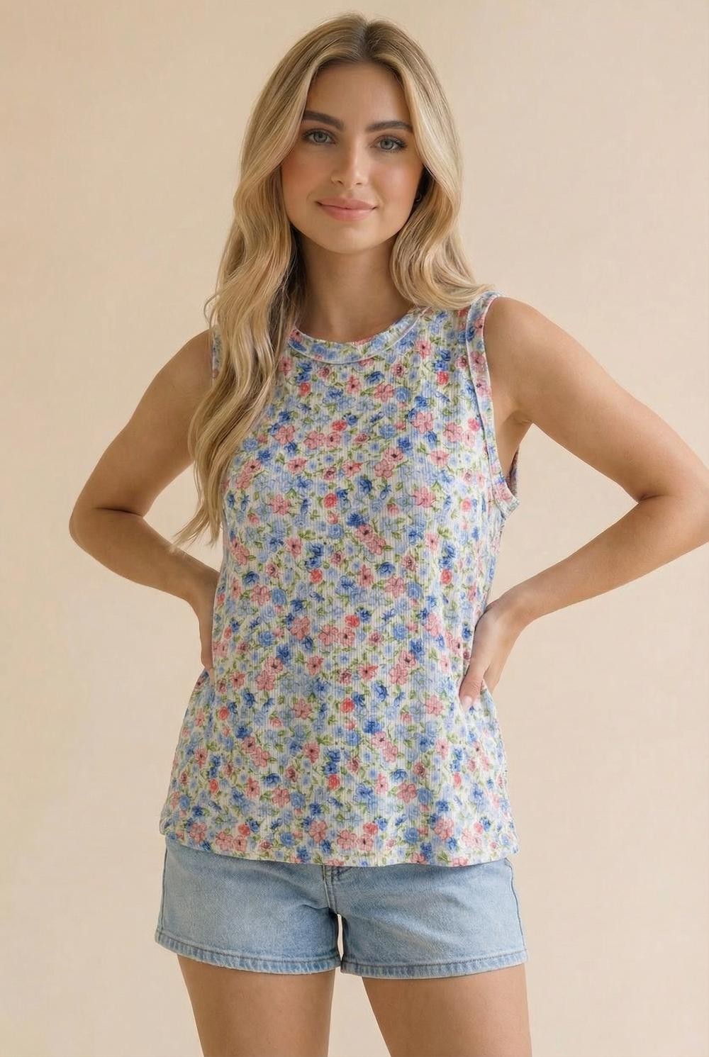 woman wearing a floral sleeveless top with a scoop neckline and light denim shorts