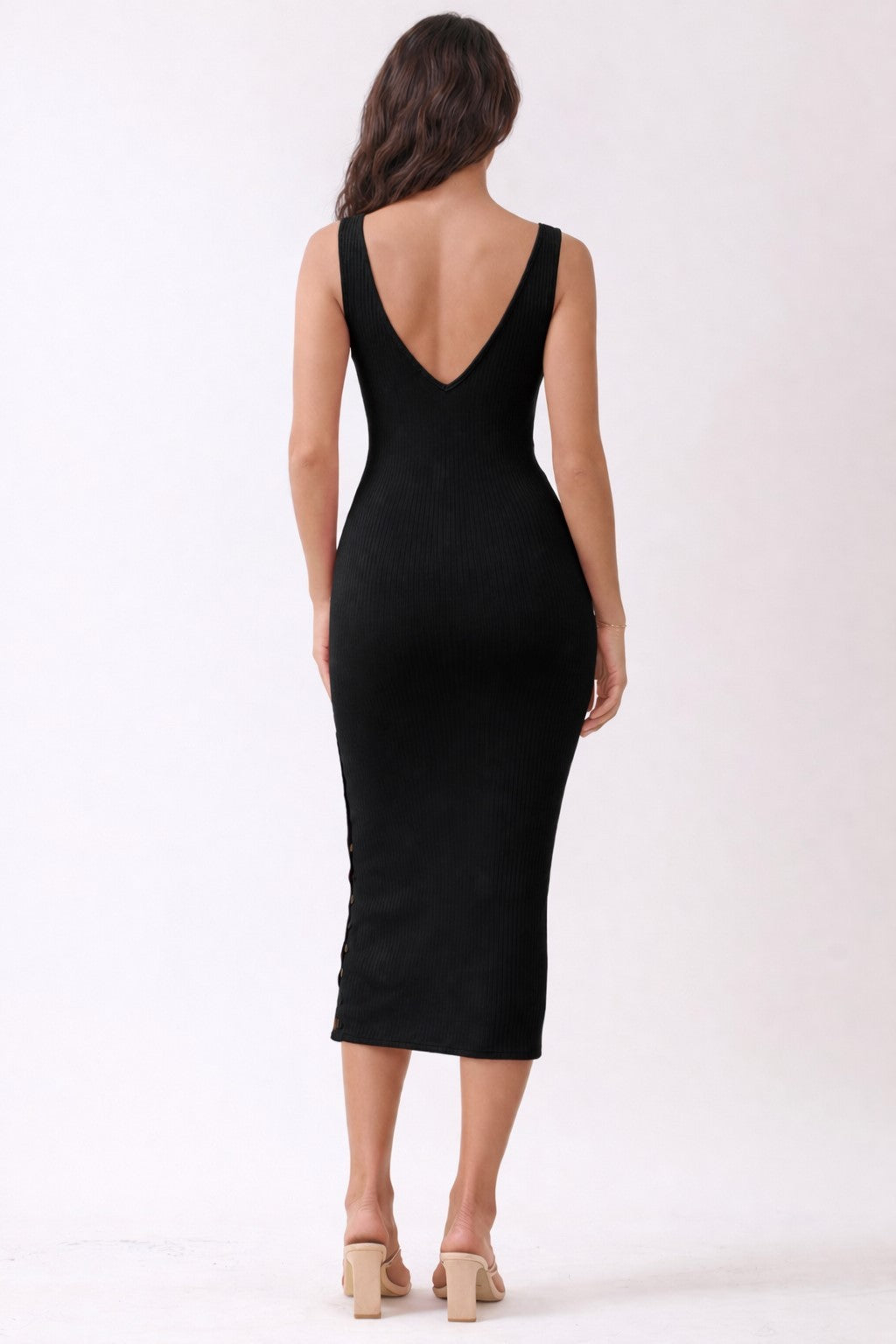 woman wearing a black ribbed midi dress with a deep v-back and fitted silhouette