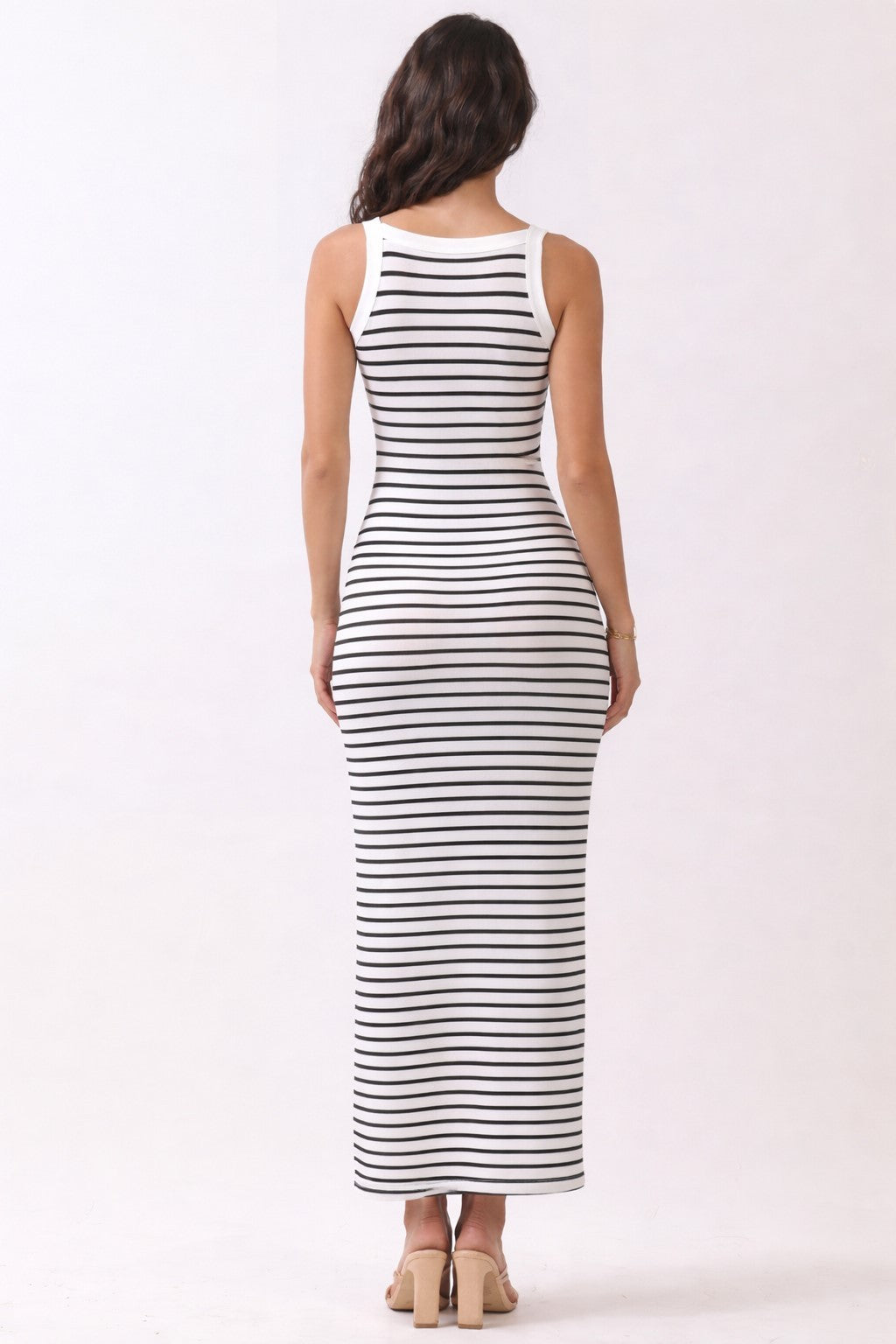 woman wearing a fitted white and navy striped maxi dress, view from the back