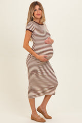 woman wearing a brown and white striped maternity dress, cradling her baby bump