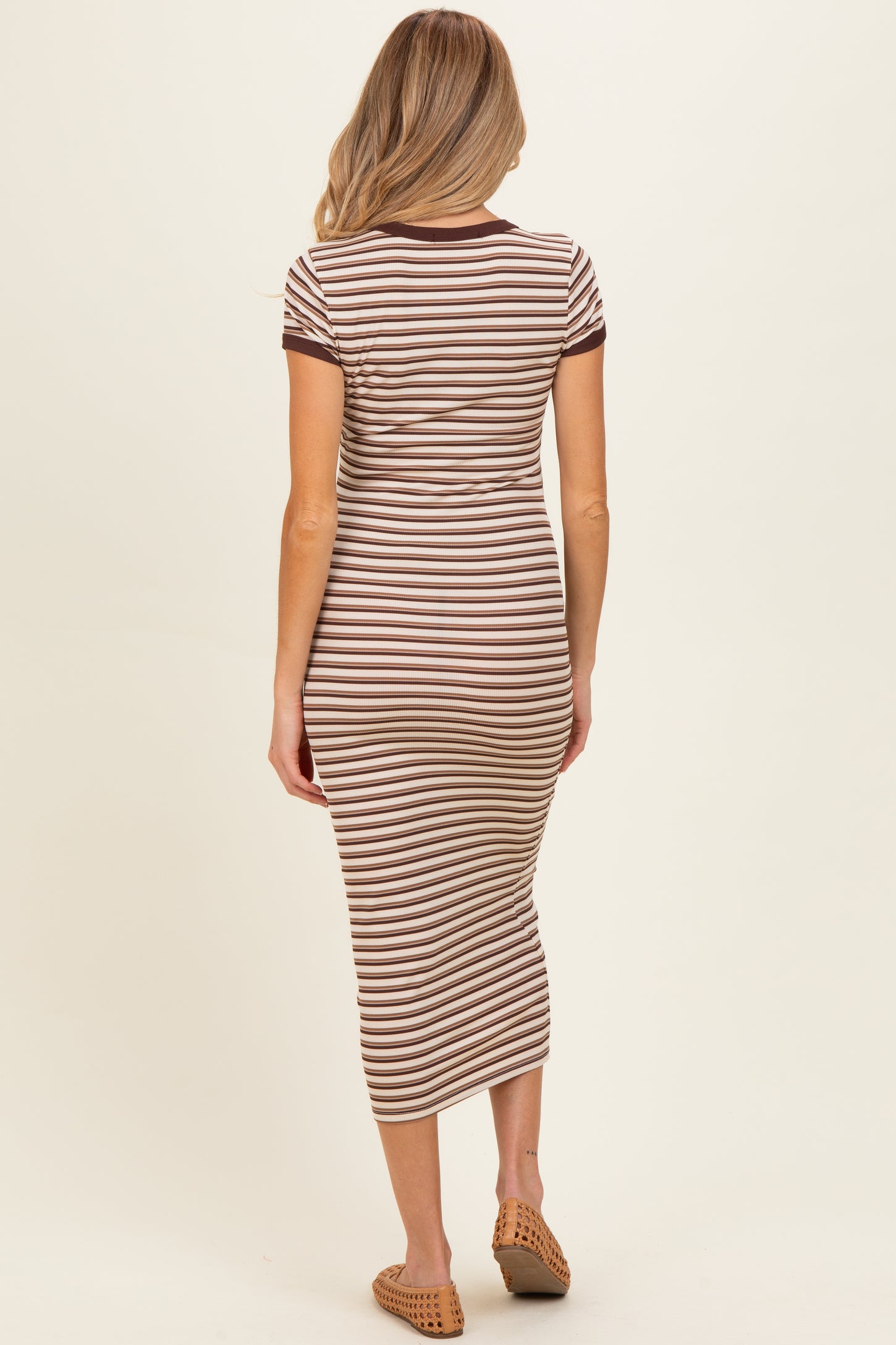 woman wearing a brown and cream striped maternity midi dress with short sleeves and a fitted silhouette