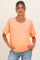 woman wearing a bright orange short sleeve maternity top and showing her baby bump