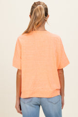 woman wearing a back view of an oversized coral maternity top with short sleeves