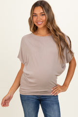 woman wearing a taupe maternity top with a relaxed fit and short sleeves, showing her baby bump