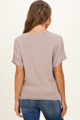 woman wearing a taupe short sleeve maternity top, viewed from the back, paired with blue jeans