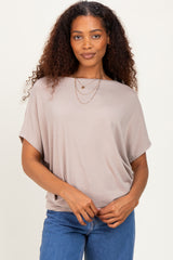 woman wearing a beige oversized short sleeve top with a round neckline and layered necklaces