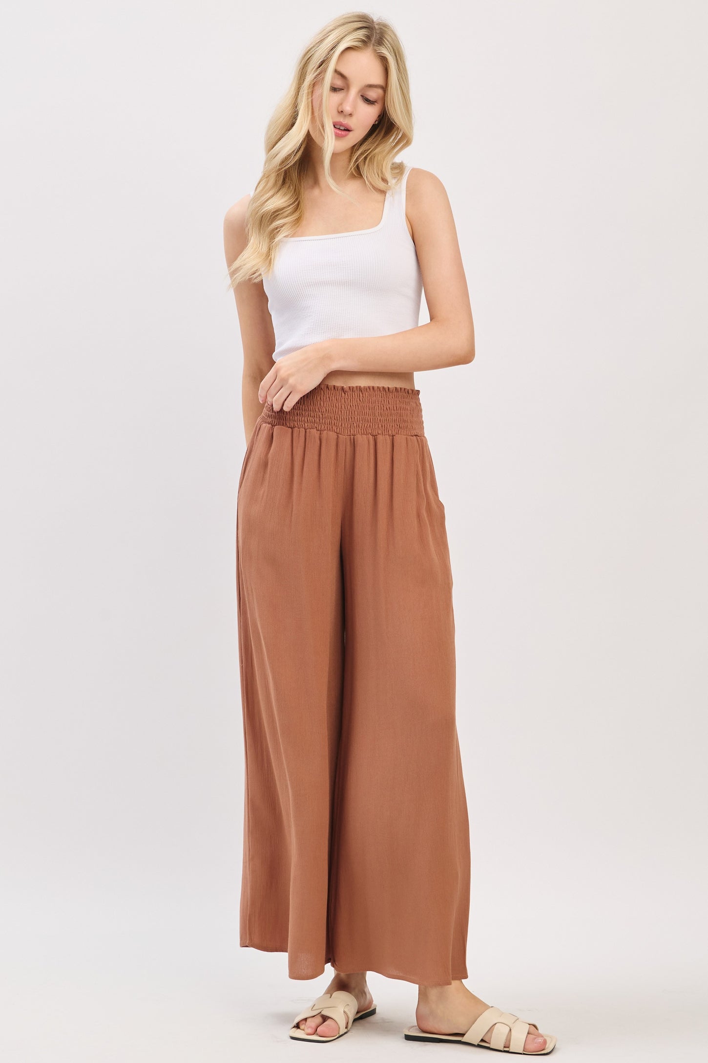 woman wearing a white square neck tank top and rust-colored wide leg pants