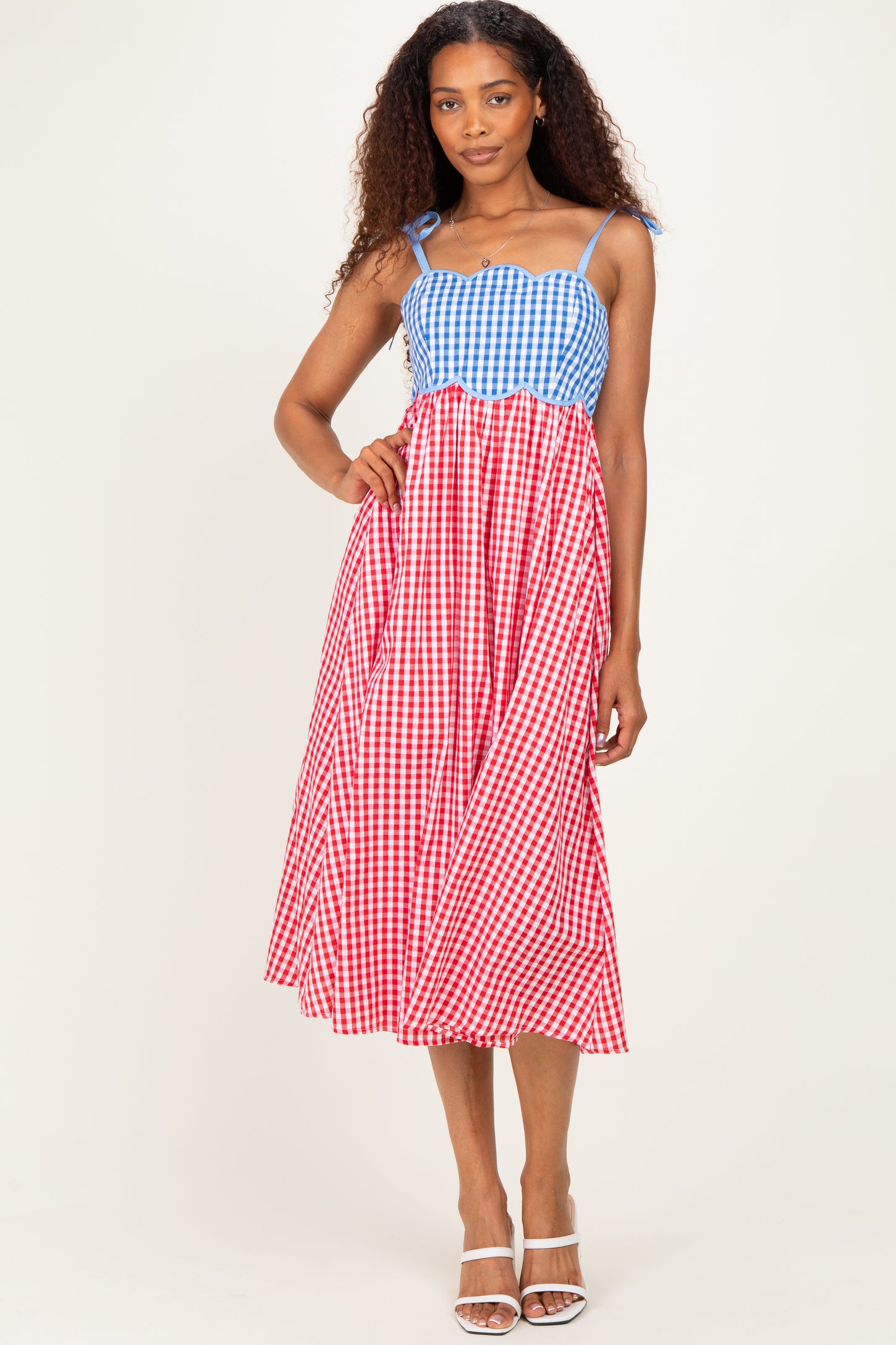 woman wearing a blue and red gingham midi dress with spaghetti straps and a tiered design