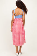 woman wearing a back view of a red and white gingham midi dress with blue smocking and tie straps