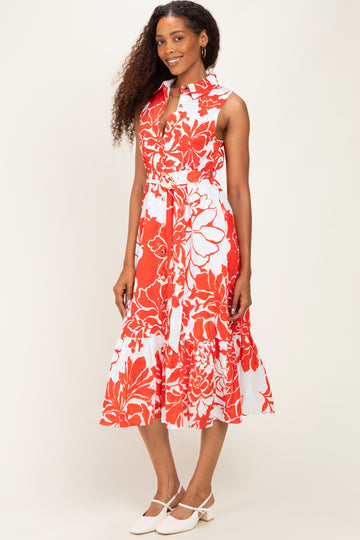 woman wearing a sleeveless red and white floral midi dress with a belt and a ruffled hem