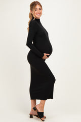 woman wearing a black long sleeve maternity dress, showing her baby bump, smiling and posing sideways