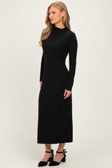 woman wearing a fitted black long sleeve maxi dress with a mock neck and side slits