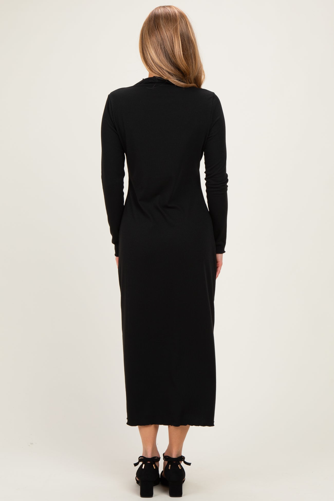 woman wearing a black long sleeve maxi dress from the back with a fitted silhouette and slight hem detailing