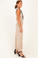 woman wearing a beige ribbed knit sleeveless dress with black trim and strappy black heels