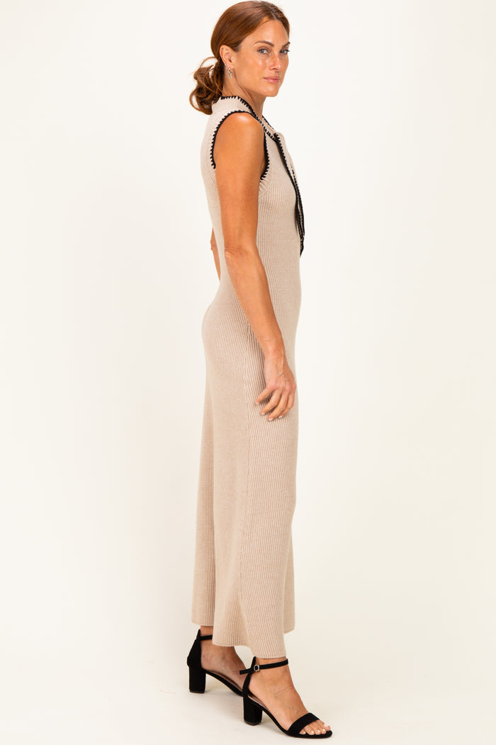 woman wearing a beige ribbed knit sleeveless dress with black trim and strappy black heels