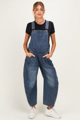 woman wearing a navy blue maternity denim overall with a loose fit and side pockets, standing against a light background