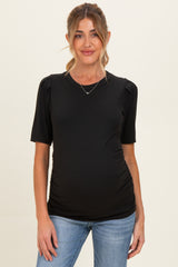 woman wearing a black short sleeve maternity top with puff sleeves and a visible baby bump