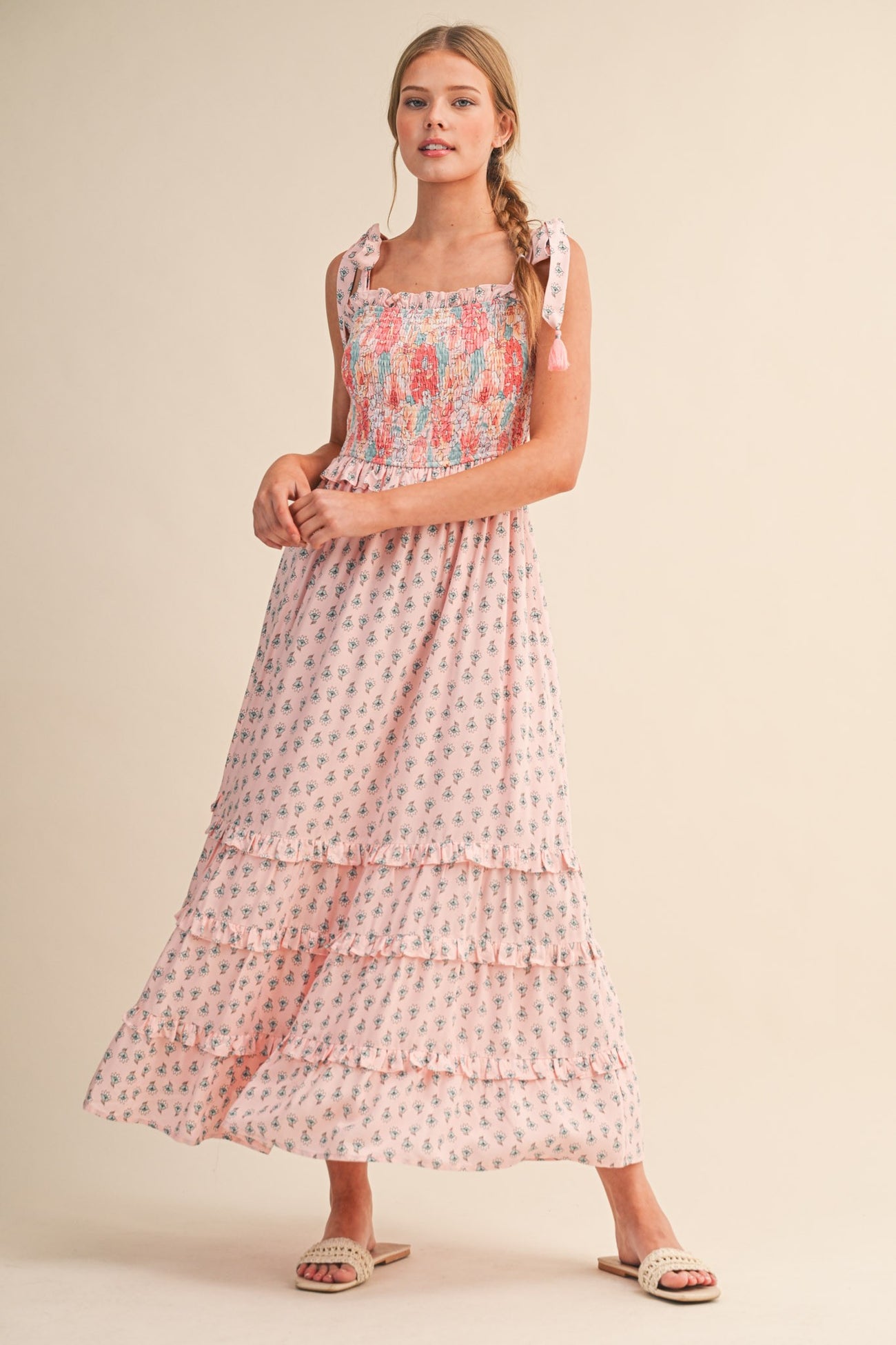 woman wearing a pink floral maxi sundress with ruffled details and tie straps