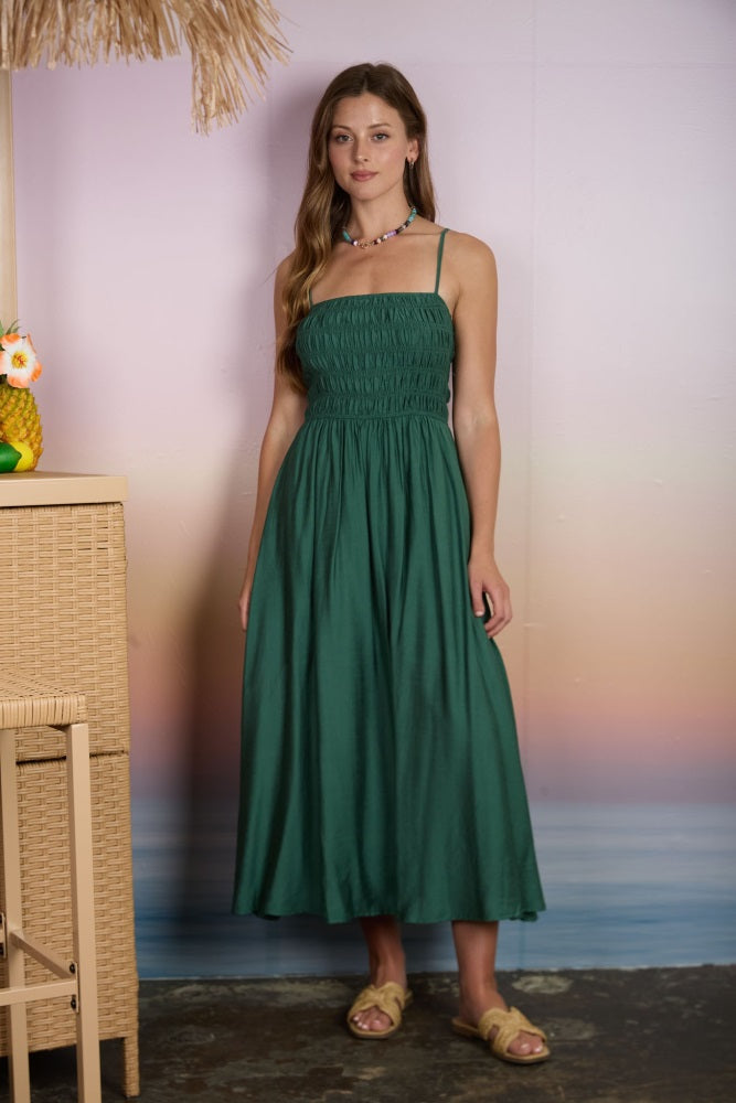 woman wearing a green smocked waist maxi dress with thin straps and a flowing skirt