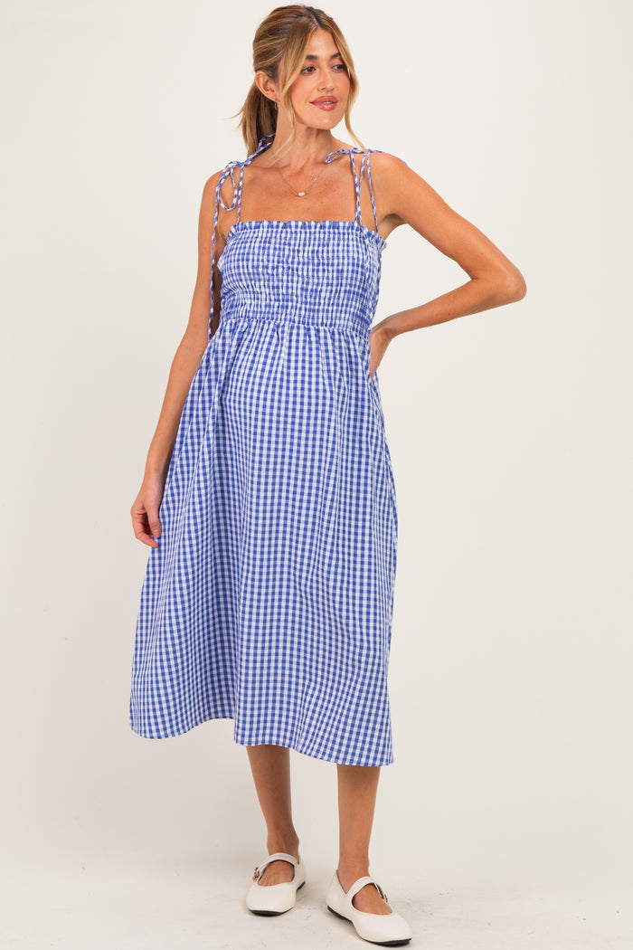 woman wearing a blue and white gingham maternity dress with adjustable straps and a visible baby bump