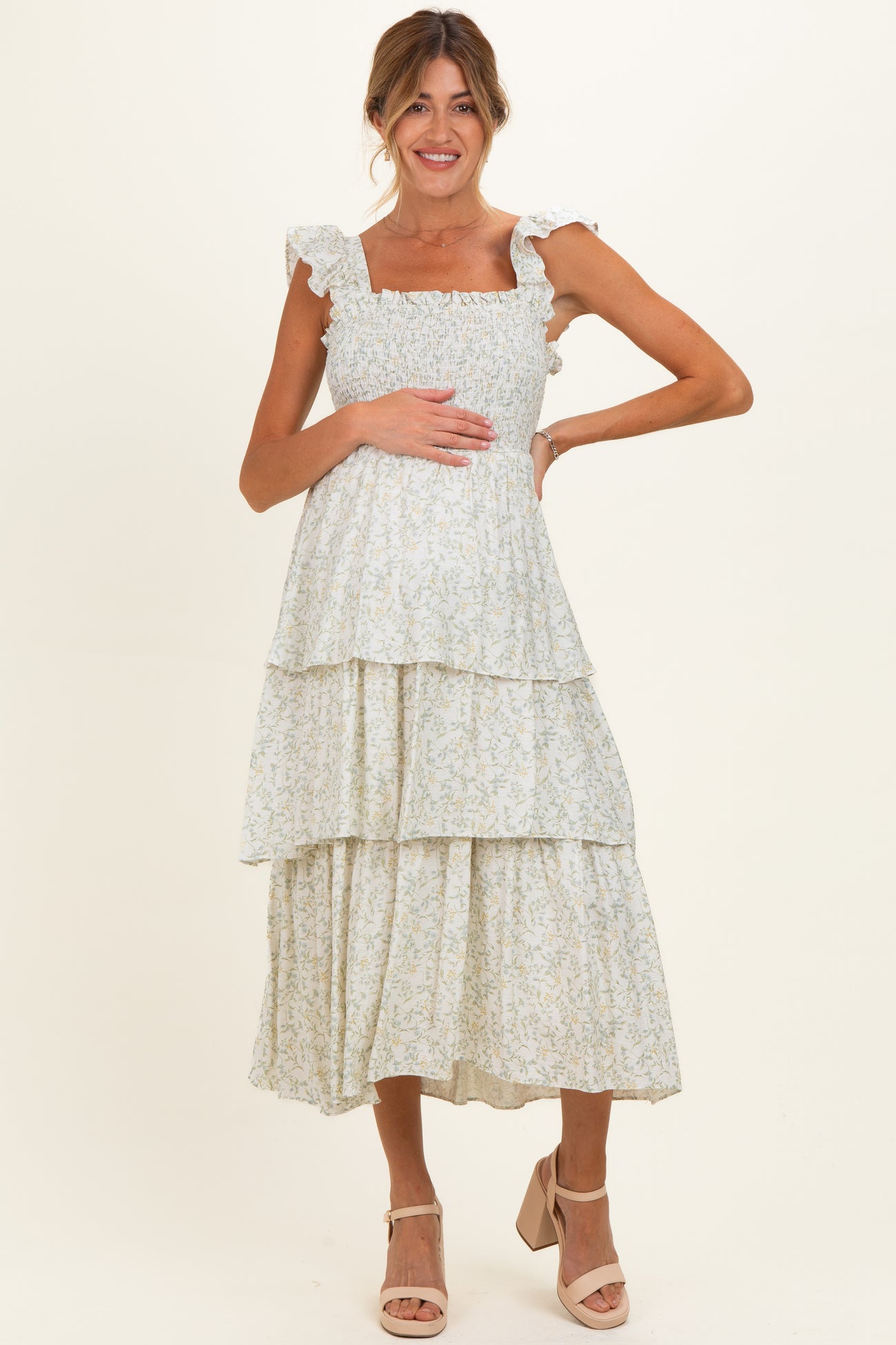 woman wearing a light floral maternity maxi dress with ruffle straps, holding her baby bump